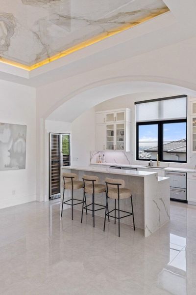 A well-lit kitchen with sleek countertops, a spacious island, and an elegant wine cooler for entertaining.