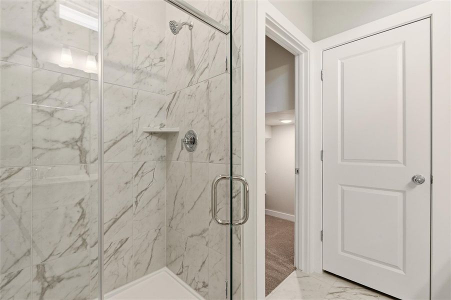 Full bath with a marble finish shower and light marble finish floors Full bath with a marble finish shower and light marble finish floors