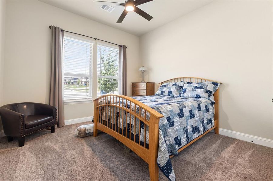 Carpeted room featuring a ceiling fan with integrated lighting, a double window with blinds and drapery, and neutral wall paint Carpeted room featuring a ceiling fan with integrated lighting, a double window with blinds and drapery, and neutral wall paint