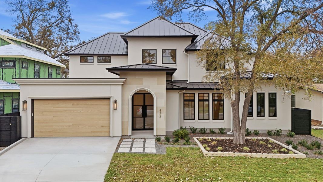View of front of property with a standing seam roof, a metal roof, concrete driveway, stucco siding, and a front yard