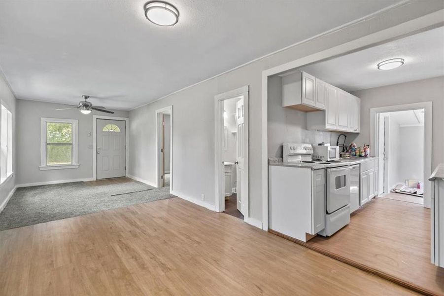 Kitchen with light hardwood / wood-style flooring, ceiling fan, electric stove, and white cabinetry Kitchen with light hardwood / wood-style flooring, ceiling fan, electric stove, and white cabinetry