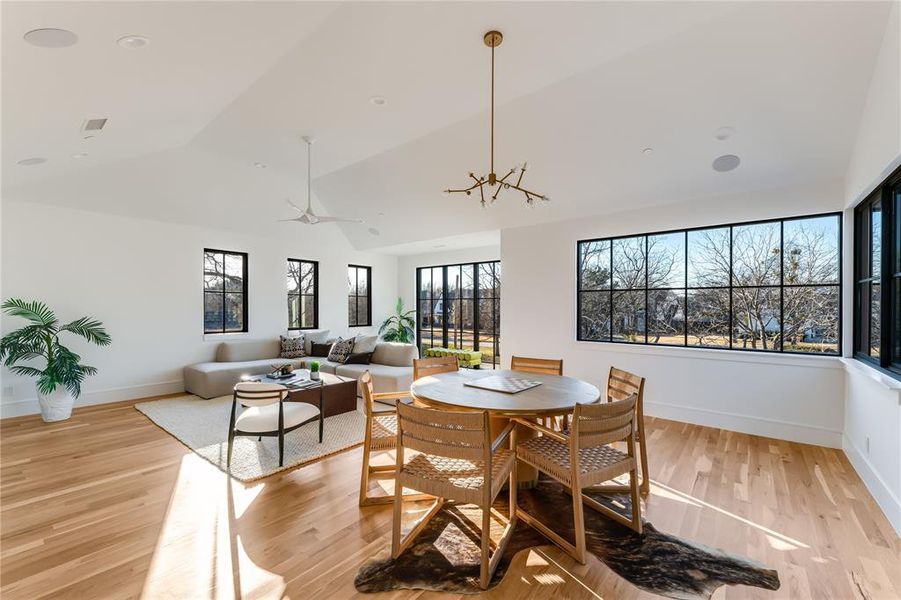 Dining room with lofted ceiling, light hardwood / wood-style flooring, and a notable chandelier