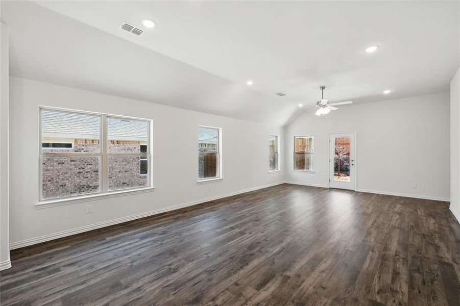 Unfurnished living room with dark wood finished floors, lofted ceiling, recessed lighting, visible vents, and baseboards