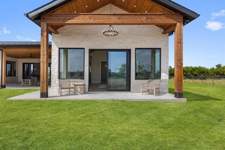 Rear view of house with a patio, a standing seam
roof, stone siding, and a metal roof Rear view of house with a patio, a standing seam
roof, stone siding, and a metal roof