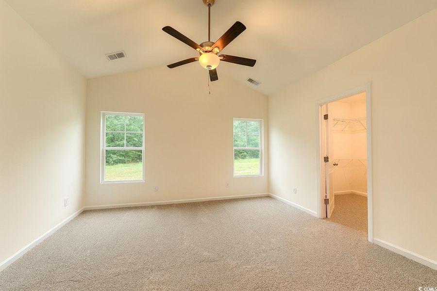 Unfurnished bedroom featuring lofted ceiling, light colored carpet, a spacious closet, and ceiling fan