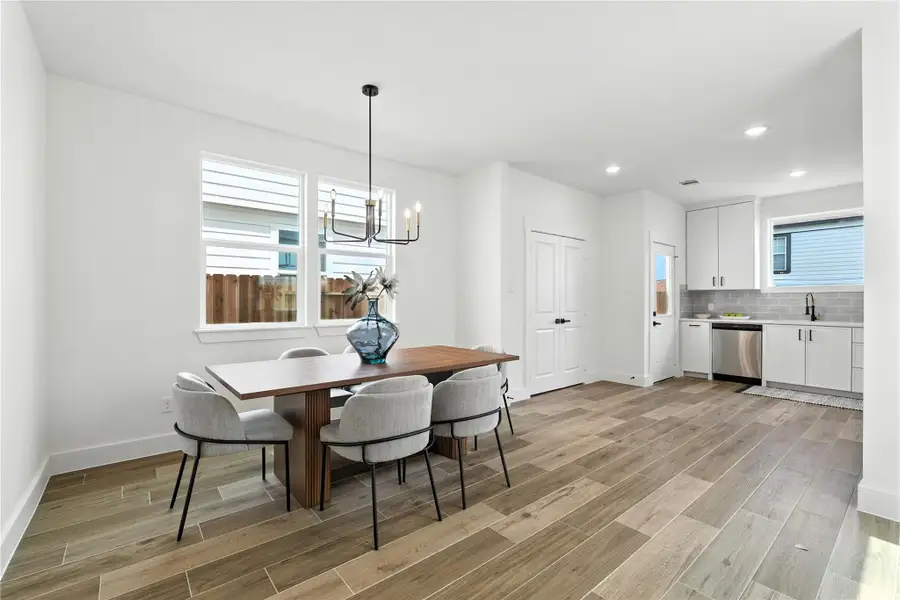 Bright and open dining area with wood-look tile floors, modern chandelier, and easy flow into the kitchen. Bright and open dining area with wood-look tile floors, modern chandelier, and easy flow into the kitchen.
