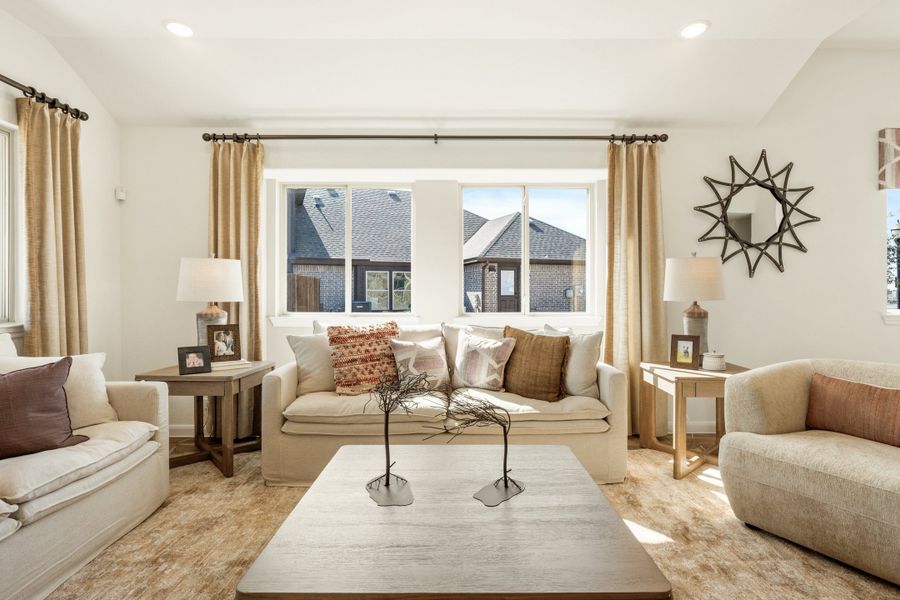 Living room with cream sofa, coffee table, large windows, and gold curtains