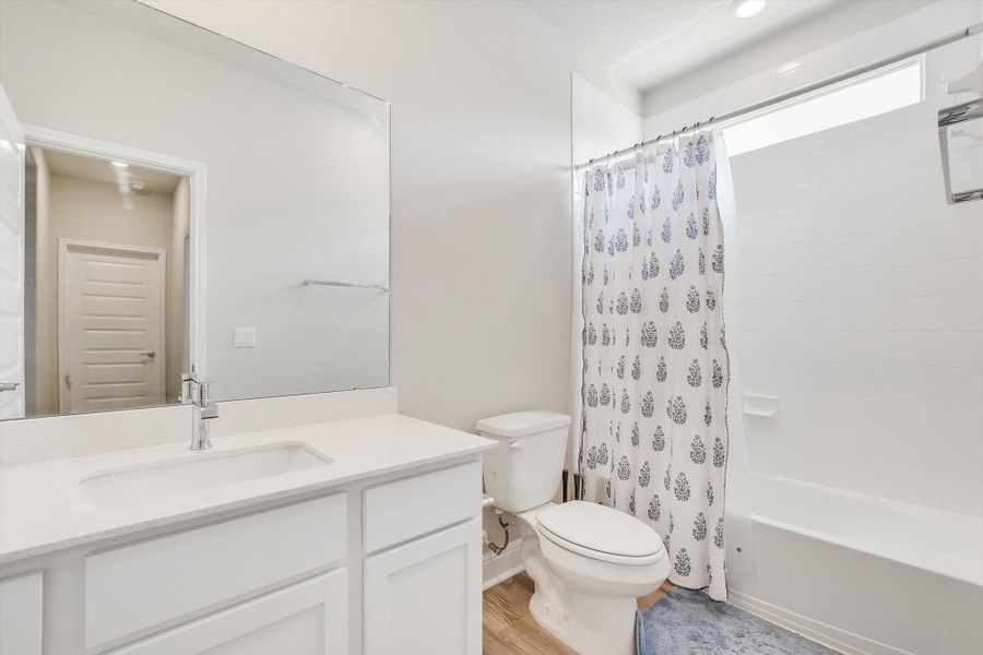 Bathroom featuring wood finished floors, vanity, toilet, and shower / bath combo with shower curtain