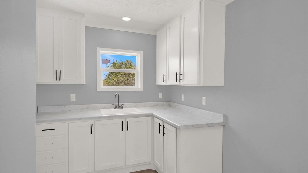 Crisp white cabinetry and stone-look countertops define this modern kitchen prep area.