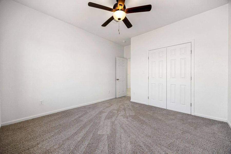 Inviting bedroom with plush carpet, generous closet space, and a sleek ceiling fan—ideal for comfort and style. Inviting bedroom with plush carpet, generous closet space, and a sleek ceiling fan—ideal for comfort and style.