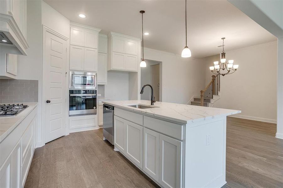 Kitchen featuring white cabinetry, stainless steel appliances, decorative backsplash, light wood-type flooring, and sink