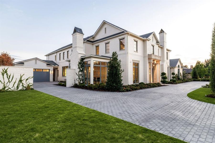 Modern farmhouse with a chimney, decorative driveway, a front lawn, and brick siding Modern farmhouse with a chimney, decorative driveway, a front lawn, and brick siding