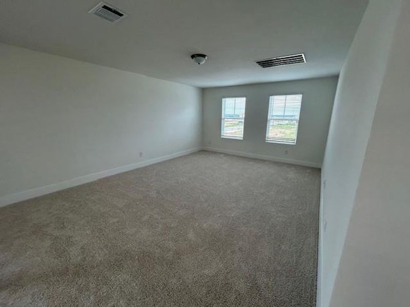 Empty room with visible vents, baseboards, and light carpet