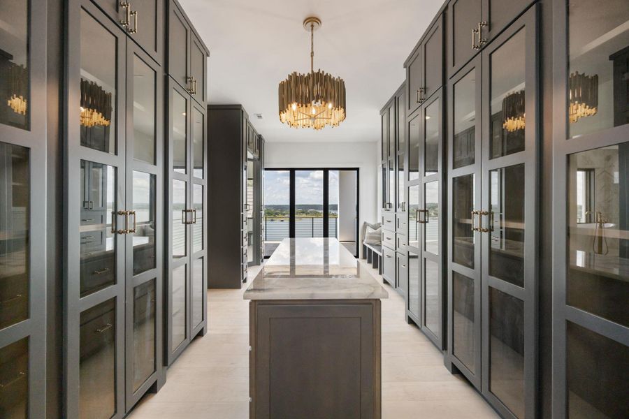 A well-lit closet with custom cabinetry and a central island offers an exceptional view. A well-lit closet with custom cabinetry and a central island offers an exceptional view.