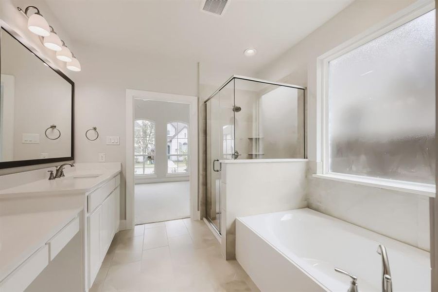 Modern bathroom featuring a double vanity with integrated sinks, a frameless glass shower enclosure, a built-in soaking tub, a large privacy window, and light-toned tile flooring