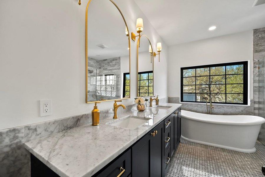 Bathroom featuring tile walls, double vanity, wainscoting, a freestanding tub, and a stall shower