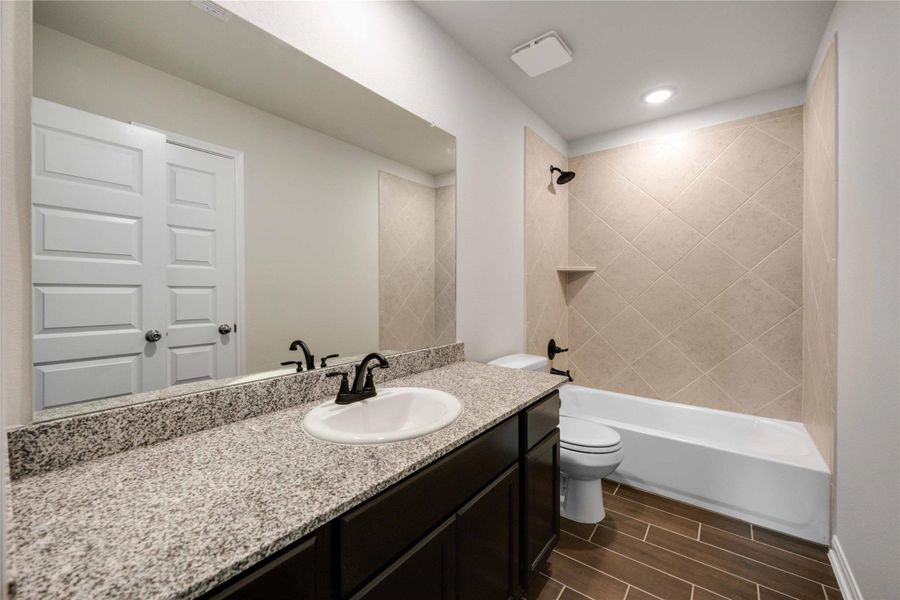 The second secondary bathroom on the second floor features extra counter space and modern finishes, including a tub/shower combo with tiled shower walls.