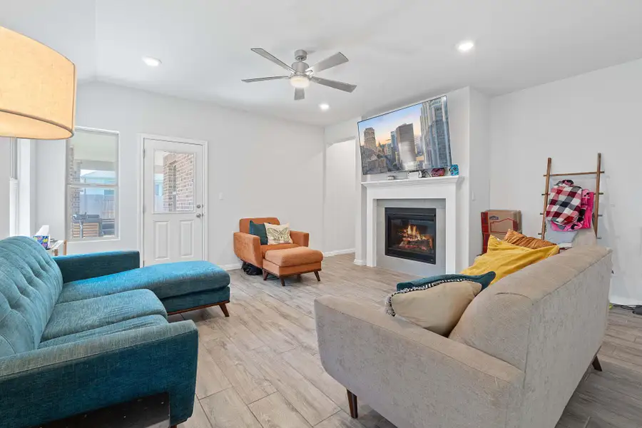 Living room with a glass covered fireplace, recessed lighting, light wood finished floors, and ceiling fan Living room with a glass covered fireplace, recessed lighting, light wood finished floors, and ceiling fan
