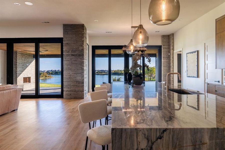 Dining area with a fireplace, sink, a water view, and light hardwood / wood-style flooring