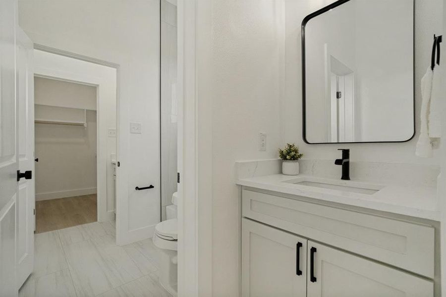 Bathroom featuring a white vanity with shaker-style cabinetry, a built-in sink, and a light-toned countertop Bathroom featuring a white vanity with shaker-style cabinetry, a built-in sink, and a light-toned countertop