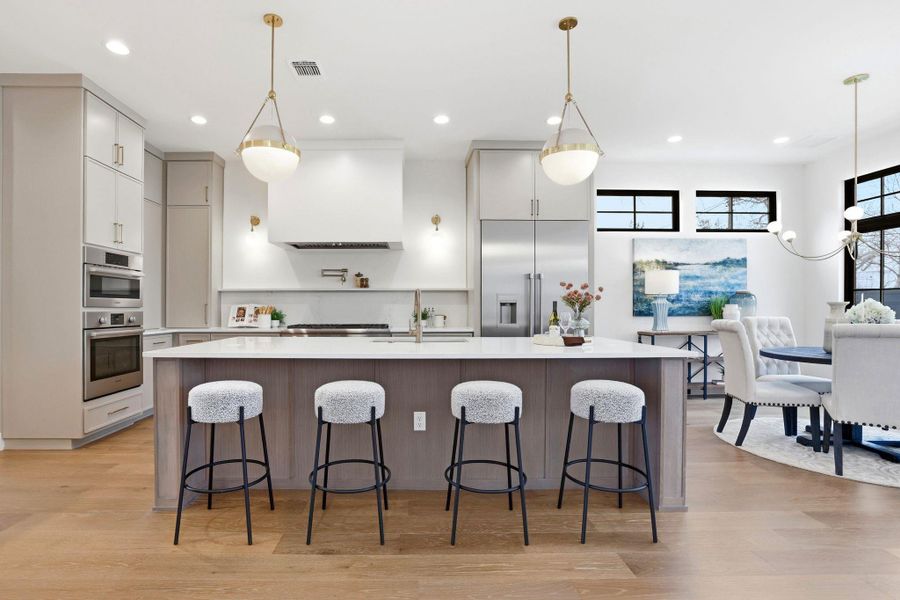Two tone kitchen with pendant lighting, a large island, light wood-type flooring, and dual tone cabinetry