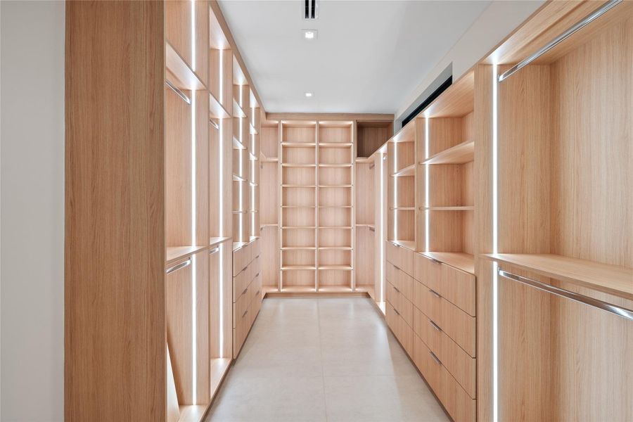 Expansive custom walk-in closet featuring sleek wood cabinetry, built-in shelving, and integrated LED lighting for a modern, organized design. Expansive custom walk-in closet featuring sleek wood cabinetry, built-in shelving, and integrated LED lighting for a modern, organized design.
