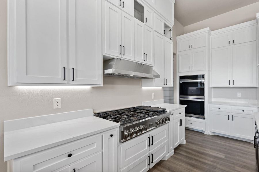 White cabinetry, sleek countertops, and high-end stainless steel appliances define this well-appointed culinary space. White cabinetry, sleek countertops, and high-end stainless steel appliances define this well-appointed culinary space.