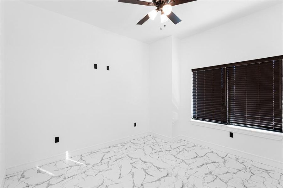 Unfurnished room with ceiling fan and marble look tile flooring