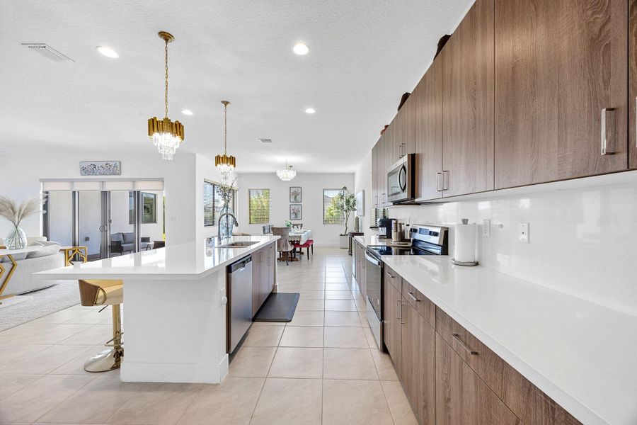 Kitchen with stainless steel appliances, a kitchen breakfast bar, decorative light fixtures, open floor plan, and modern cabinets