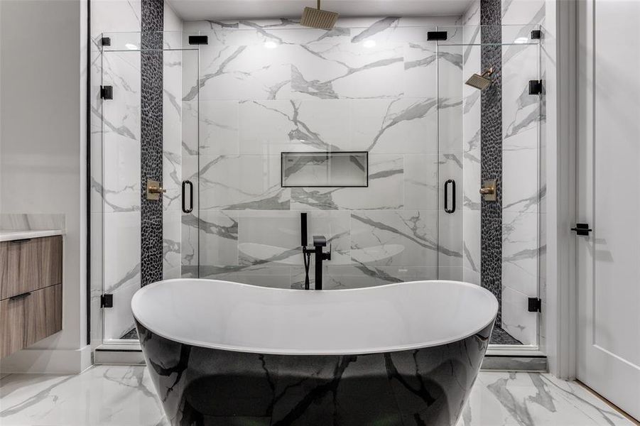 Full bathroom featuring marble tiled floors, a freestanding bath, and a marble finish shower