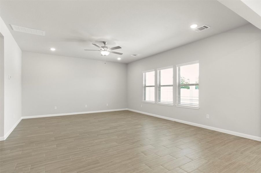 Empty room featuring ceiling fan, baseboards, light wood-type flooring, and recessed lighting
