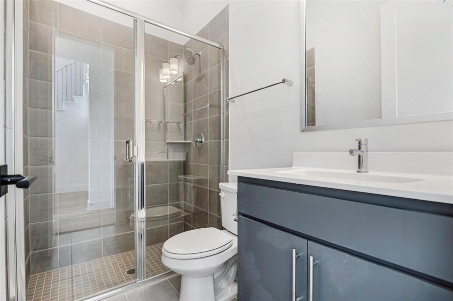 Bathroom featuring toilet, a stall shower, and vanity