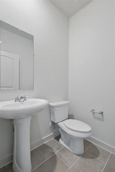 Half bathroom with baseboards and tile patterned floors