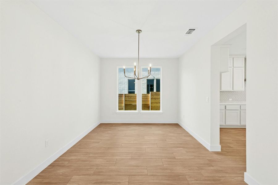 Unfurnished dining area with a chandelier and light wood-type flooring
