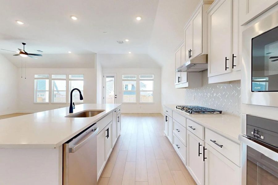 The kitchen features white cabinetry, stainless steel appliances, a gas cooktop, and a white tile backsplash