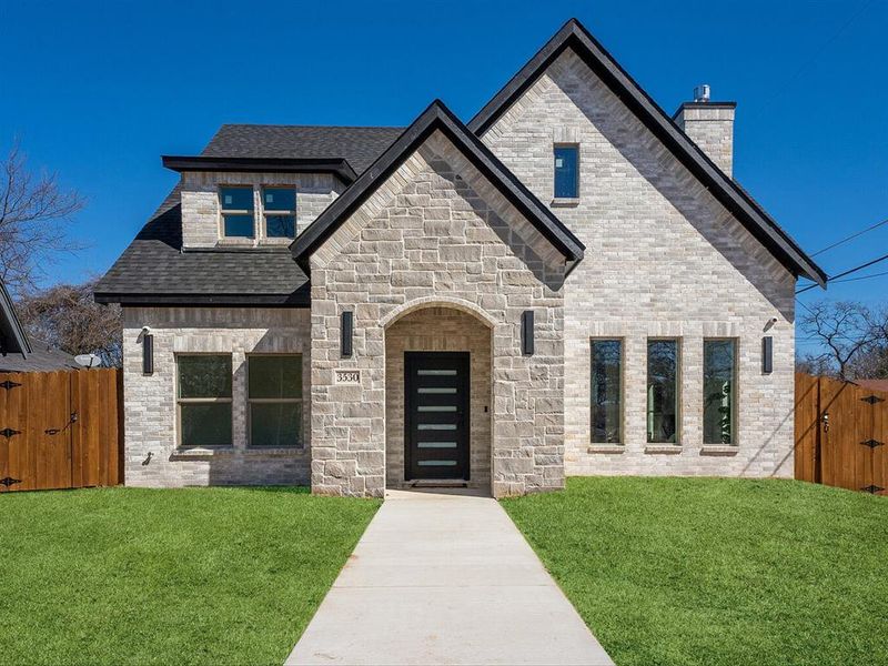 French country style house featuring a gate, brick siding, and a front lawn