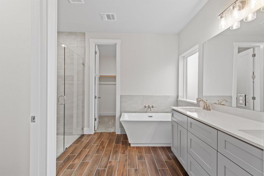 Bathroom featuring plus walk in shower, tile walls, and vanity