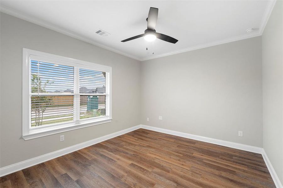 Empty room featuring baseboards, visible vents, ornamental molding, and dark wood finished floors