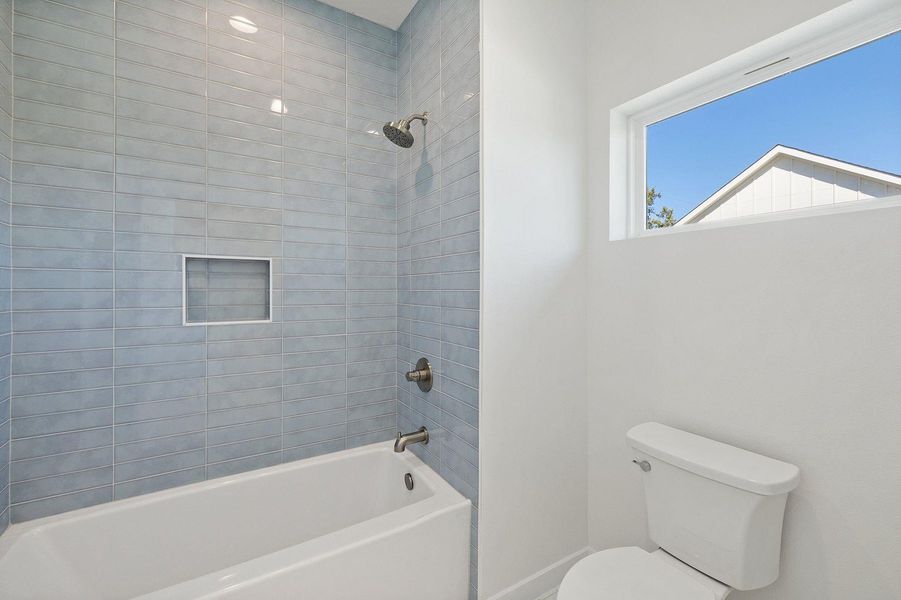 Bathroom with toilet, baseboards, and shower / bathing tub combination