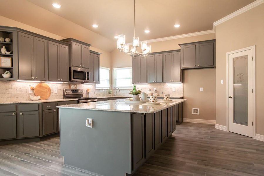 Kitchen featuring open shelves, appliances with stainless steel finishes, light stone counters, a chandelier, and a center island Kitchen featuring open shelves, appliances with stainless steel finishes, light stone counters, a chandelier, and a center island