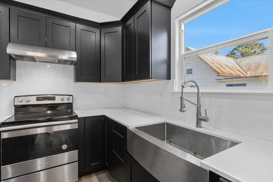 Dark cabinets contrast beautifully with clean white countertops and a modern farmhouse sink. Dark cabinets contrast beautifully with clean white countertops and a modern farmhouse sink.