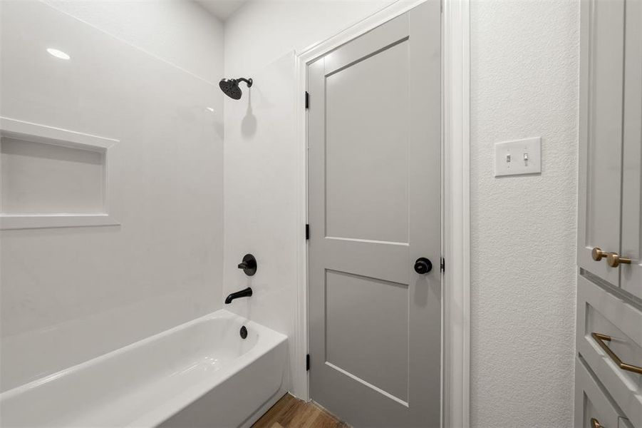 Bathroom with shower / washtub combination and light wood finished floors Bathroom with shower / washtub combination and light wood finished floors