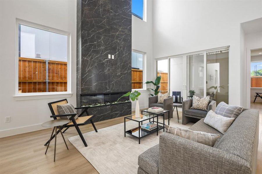 Living room featuring a high ceiling, a high end fireplace, and light wood-type flooring