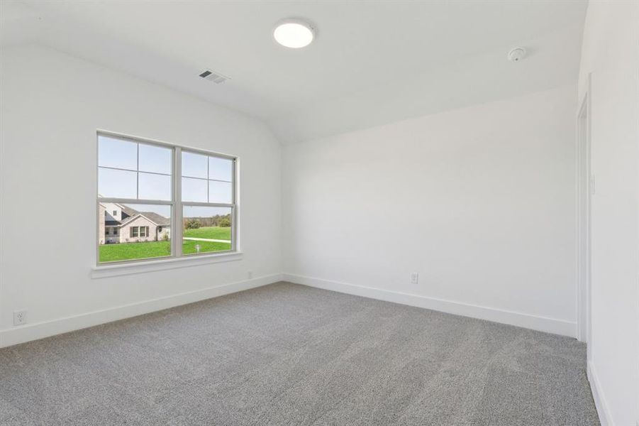 Unfurnished room with vaulted ceiling and light colored carpet