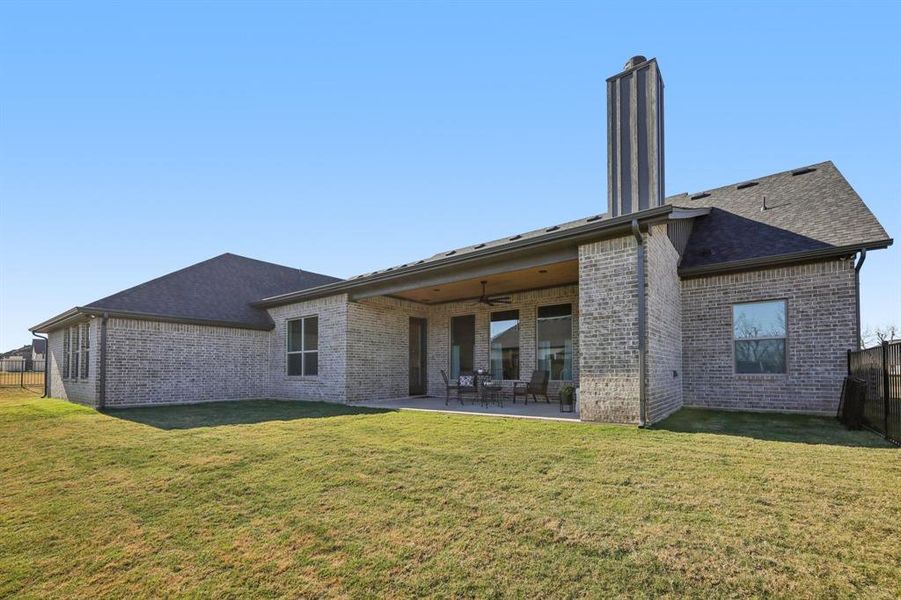 Back of house featuring a ceiling fan, a patio area, brick siding, and a chimney Back of house featuring a ceiling fan, a patio area, brick siding, and a chimney