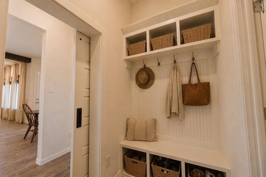 Built-in mudroom bench with beadboard backing, overhead shelving, and storage cubbies