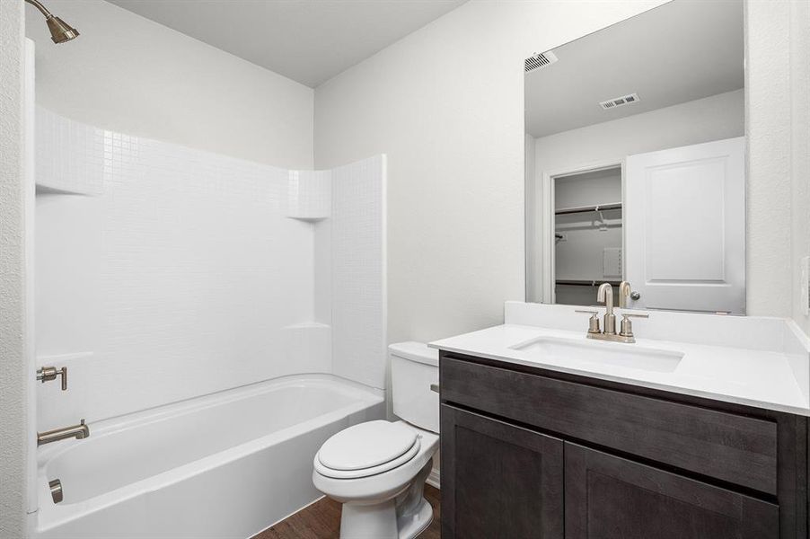 Full bathroom with vanity, wood finished floors, toilet, and bathing tub / shower combination Full bathroom with vanity, wood finished floors, toilet, and bathing tub / shower combination