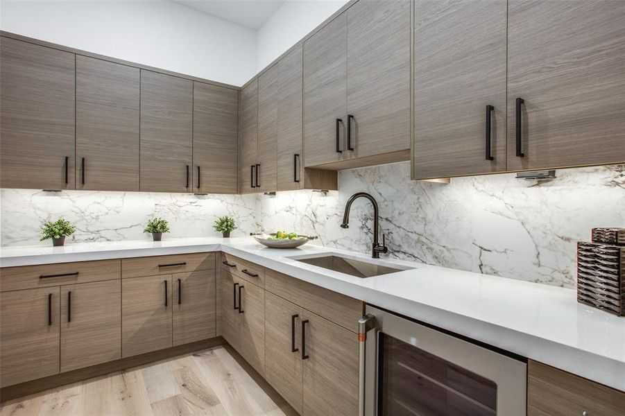 Kitchen with decorative backsplash, light hardwood / wood-style flooring, beverage cooler, and sink