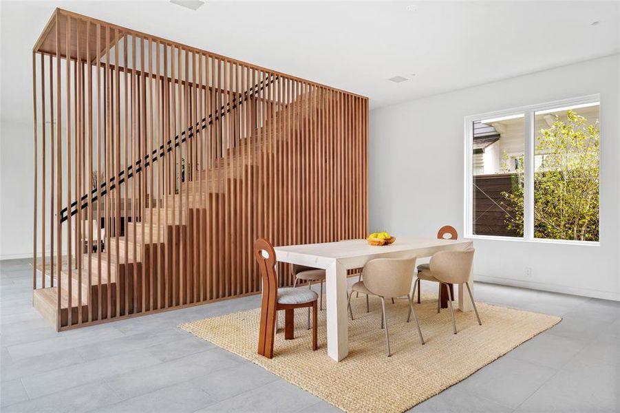 The elegant formal dining area, located just off the kitchen, features a minimalist design and is enhanced by a custom slatted walnut staircase - creating an inviting atmosphere perfect for family meals or entertaining guests.