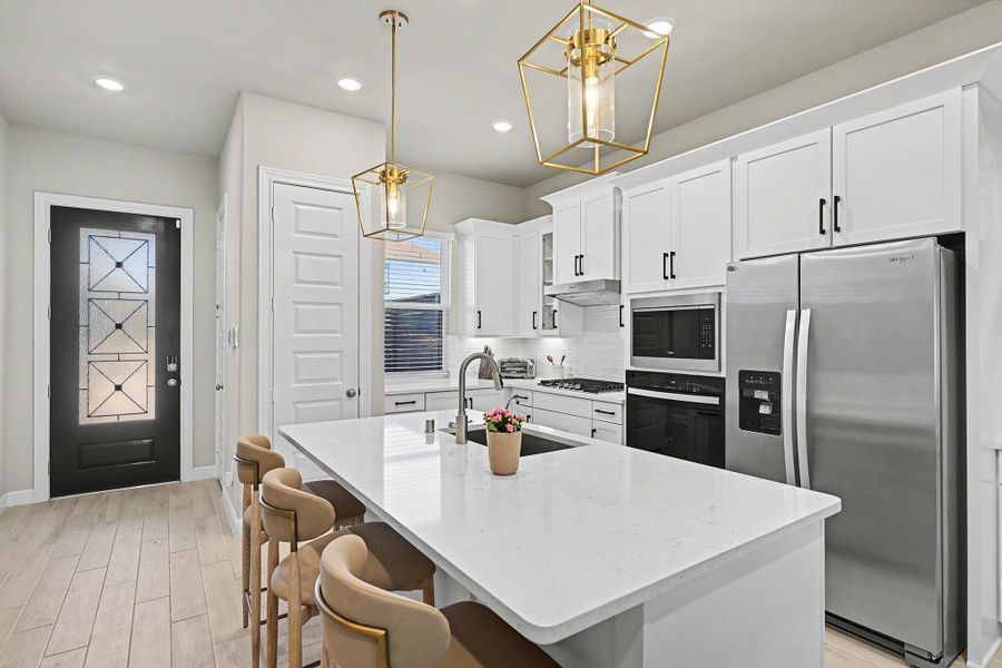 The kitchen pairs quartz countertops and a spacious island. The kitchen pairs quartz countertops and a spacious island.